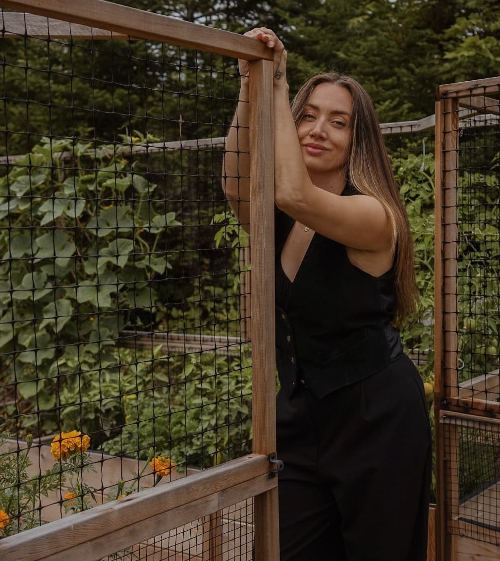 Caley Dimmock leaning in the gate of her garden beds